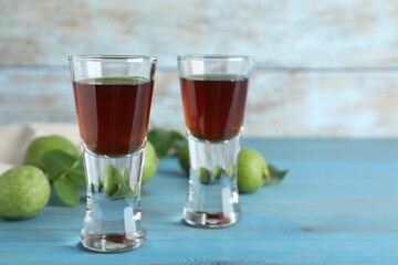 Delicious liqueur and green walnuts on light blue wooden table, space for text