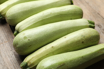 Raw green zucchinis on wooden table, closeup