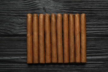 Many cigars on black wooden table, flat lay