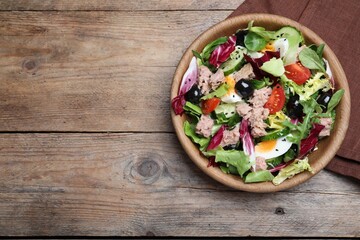 Bowl of delicious salad with canned tuna and vegetables on wooden table, flat lay. Space for text