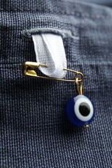 Naklejka premium Evil eye safety pin on clothing, closeup