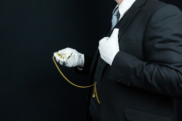 Profile Portrait of Butler in Dark Suit and White Gloves Holding Gold Pocket Watch. Concept of Service Industry.