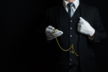 Portrait of Butler in Dark Suit and White Gloves Holding Gold Pocket Watch. Vintage Style and...