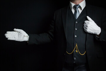 Portrait of Butler in Dark Suit and White Gloves Standing With Welcoming Gesture. Concept of Service Industry and Professional Hospitality. - obrazy, fototapety, plakaty