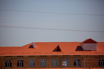 Roofs of houses from a metal profile against the sky. Roofing. Metal tiles on the roofs of houses.