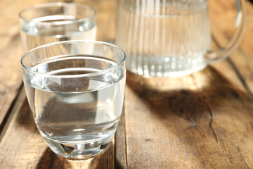Glass of water on wooden table, closeup. Refreshing drink
