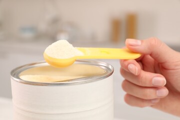 Woman with powdered infant formula indoors, closeup. Preparing baby milk