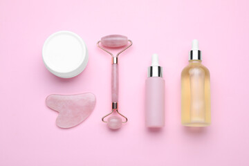 Obraz na płótnie Canvas Natural face roller, gua sha tool and cosmetic products on pink background, flat lay