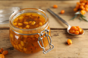Delicious sea buckthorn jam and fresh berries on wooden table, closeup. Space for text