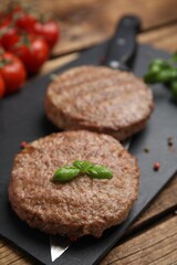 Tasty grilled hamburger patties served on wooden table, closeup