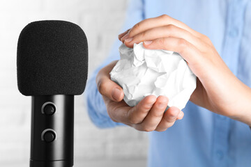 Woman making ASMR sounds with microphone and crumpled paper, closeup