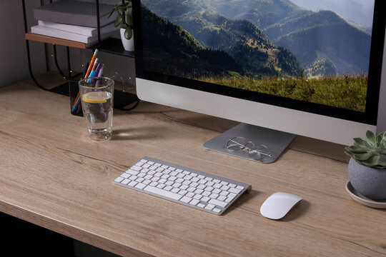 Modern computer and glass of lemon water on wooden table indoors
