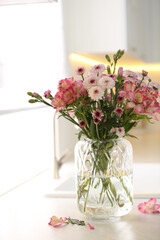 Vase with beautiful flowers on kitchen counter. Stylish element of interior design