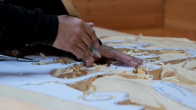 The carpenter creates a carved picture. Hands of the master close-up