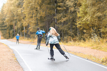 Women ride roller skis in the autumn Park.