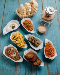 Assorted bahraini breakfast set table with bread, coffee, tea, kababs, donut, vegetables isolated on wooden table side view