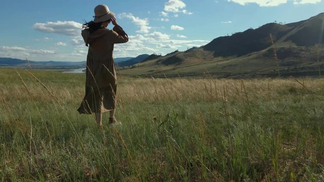 slow motion footage of walkinig young asian girl in dress and hat on the meadow in summer. like anime