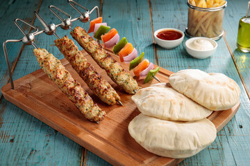 chicken seekh kabab with bread, dip, sauce and fries isolated on cutting board side view on table fastfood