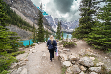 Obraz premium Woman carrying camera gear walks the Rockpile Trail at Moraine Lake in Banff National Park
