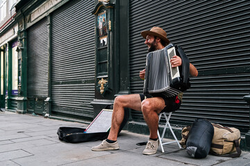 young man with bearded musician playing accordion in a tourist street in portugal lisbon, asking...