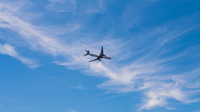 Airplane Flying In The Blue Cloudy Sky