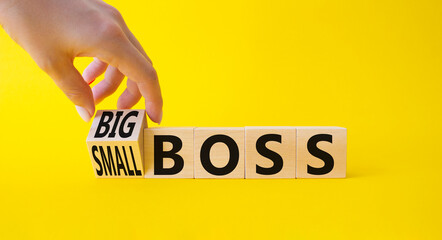 Big vs small boss symbol. Businessman hand turnes wooden cubes and changes words Small boss to Big boss. Beautiful yellow background. Business concept. Copy space.