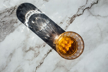 photography of scotch whisky glass in a marble table with light and shadow