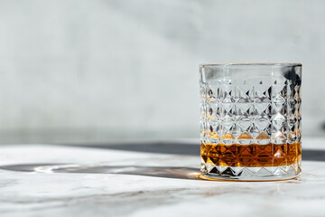 photography of scotch whisky glass in a marble table with light and shadow