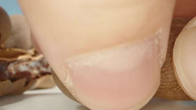 I peel the tamarind fruit from the shell, extreme close-up. Slow motion