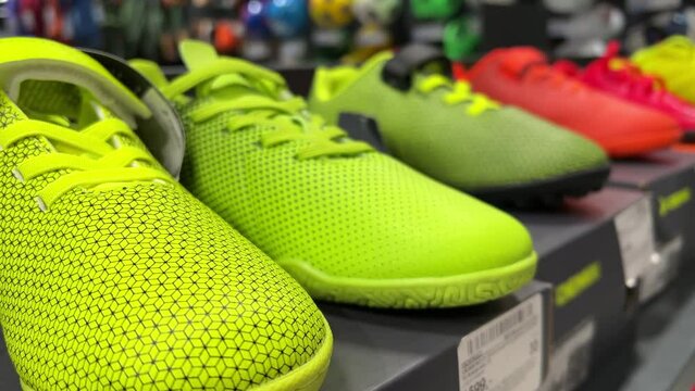 New running shoes in bright green and red are lined up on the shelf of a sports shoe store. Closeup