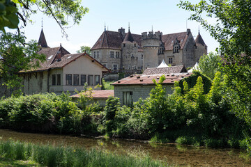 Village in the Jura in France with a castle, a river and trees
