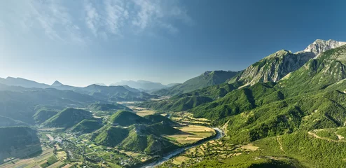 Foto op Aluminium Aerial panoramic view of the Vjose River valley in Albania. The crystal clear, turquoise river winds its way through fields against a backdrop of majestic mountains. Blue skies, summer.  © Martin Mecnarowski