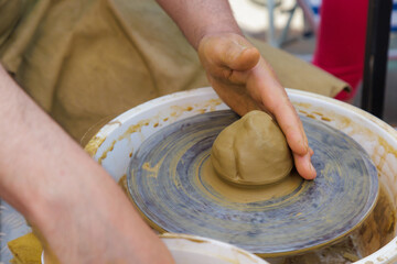 Potter in the process of working on a potters wheel. Close-up hands. Background with copy space