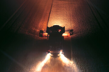 Harvester harvesting wheat in the field at night, bright lights illuminate the wheat in the field...