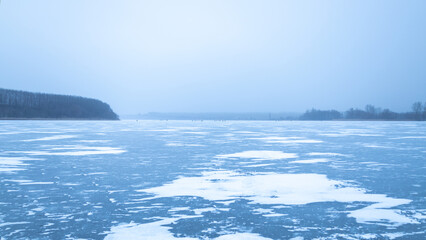 Winter landscape on a frozen river at sunset, heavy frost and a frozen river in winter, everything is covered with snow