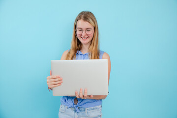 Naklejka premium Smiling, successful, energetic blonde woman in eyeglasses working on laptop on blue isolated background. Trader course