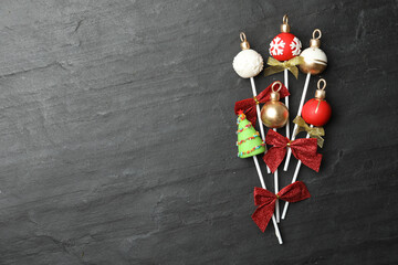 Delicious Christmas themed cake pops on black table, flat lay. Space for text