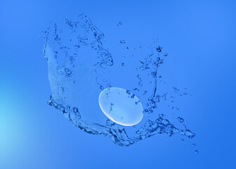 Contact lens and splash of solution on blue background