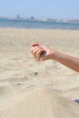 Child pouring sand from hand on beach, closeup. Fleeting time concept