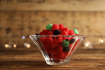 Delicious jelly candies in bowl on wooden table, closeup
