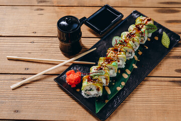 There are a exotic sushi on the decorative black plate in the Japanese restaurant.