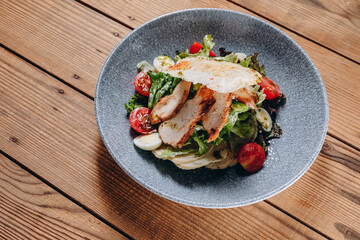There is a salad with slices of meat on the bowl in the cafe.