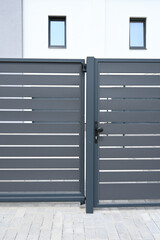 High grey fence. Modern barrier aluminum slats. Modern stone fence with metal shutters