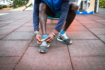 black man in sportswear, laces up his sneakers to start running.	
