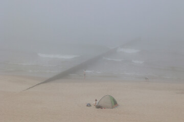 Mgła wisi nad plażą morza bałtyckiego. Słabo widać.