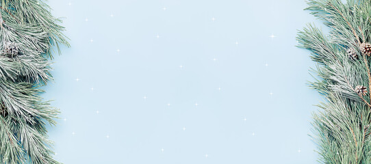 festive Christmas background - fir branches in the snow on the sides of the banner, on a blue background, copy space