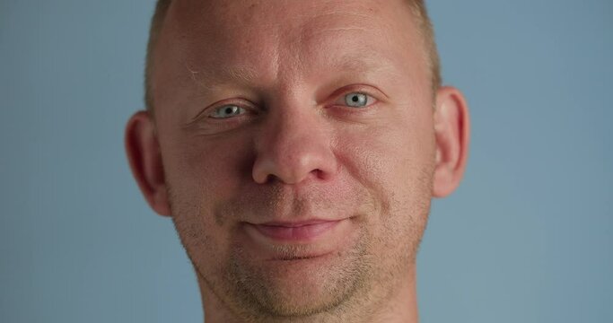 Man playfully winking looking at camera with optimistic smile, close-up