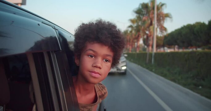 a proud African boy looks out of the car window and looks into the camera. A young dreamer who knows what he wants.