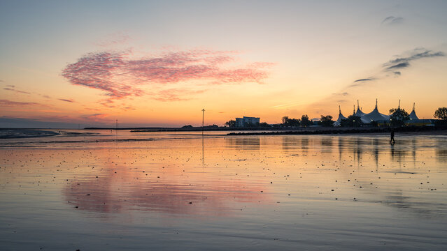 Sunrise reflections on Minehead beach with a silhouetted Butlins