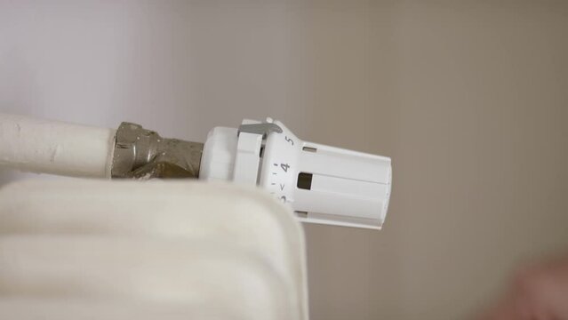 Close up of a hand turning up the temperature of a radiator.
